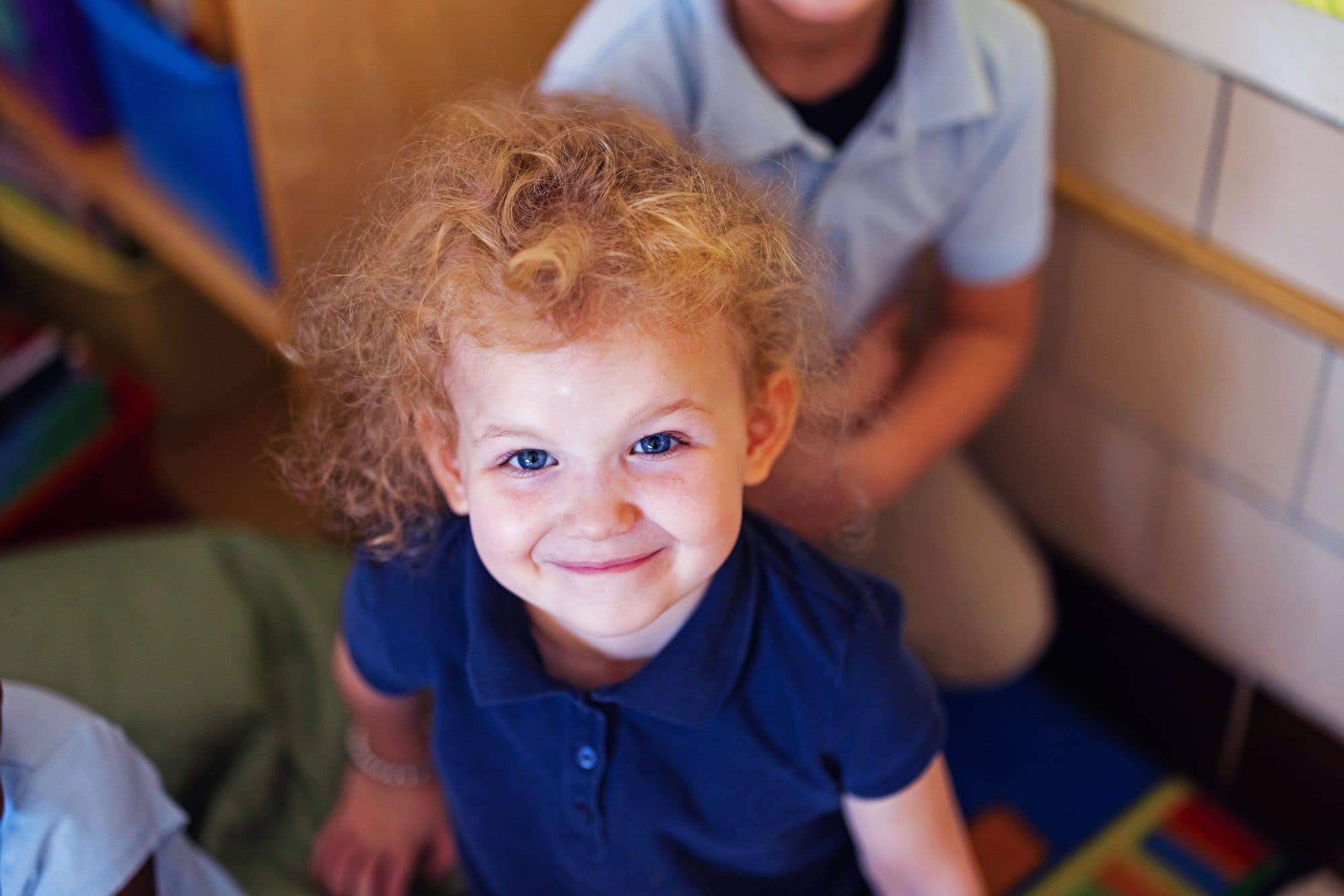 Smiling student with curly blonde hair wearing a blue polo shirt.