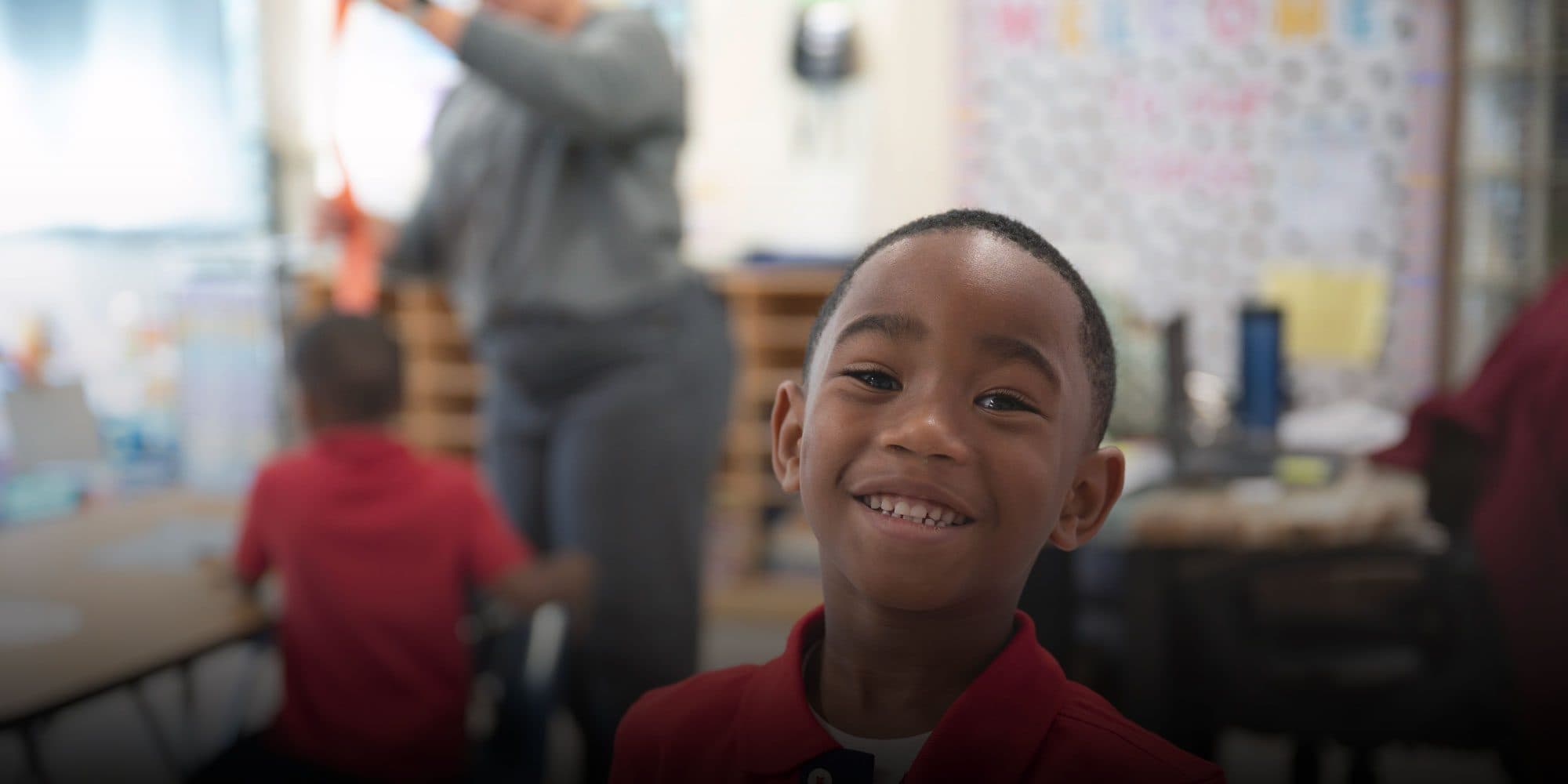 Smiling student in a red shirt in a Foundation Academy classroom.