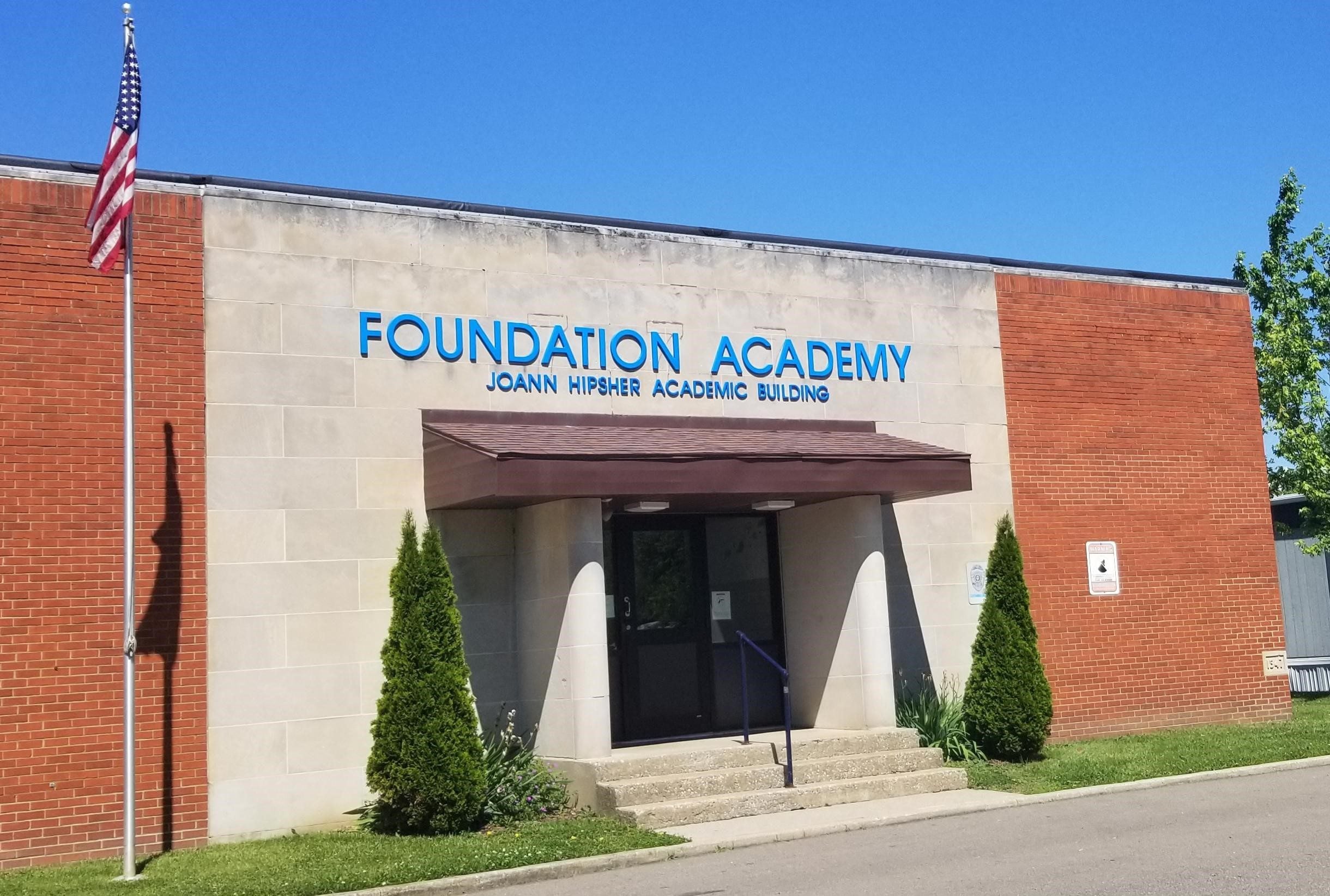 Exterior of Foundation Academy building with flag and entrance.